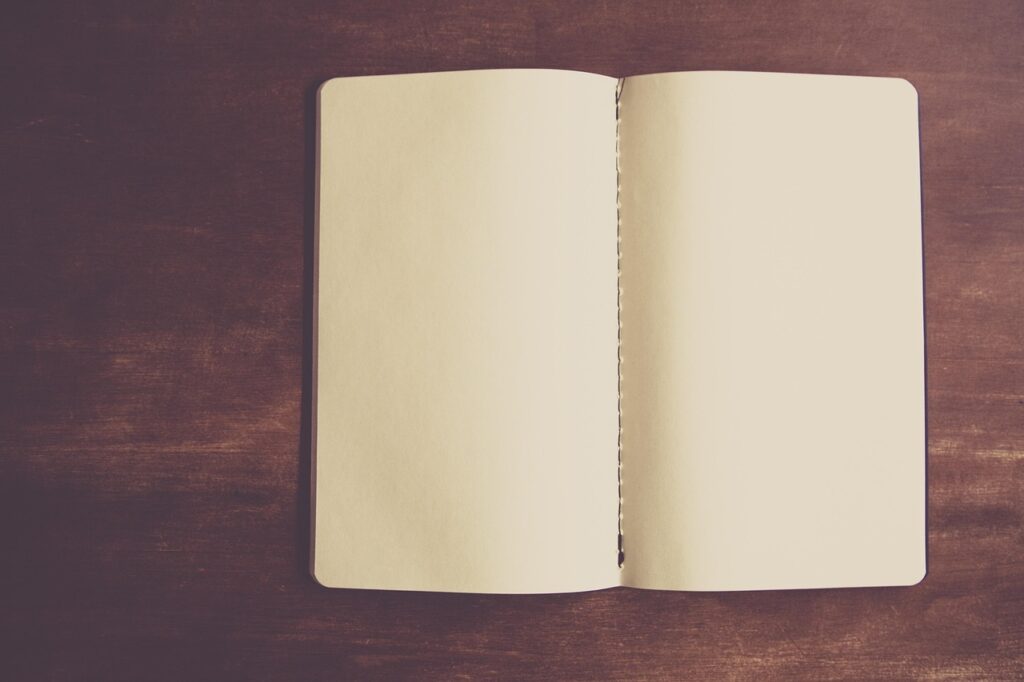 An open blank notebook on a wooden desk, representing drafting a simple AI usage policy