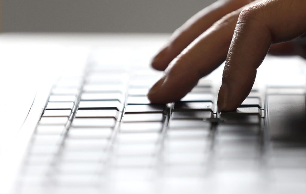 Close-up of fingers typing on a laptop keyboard