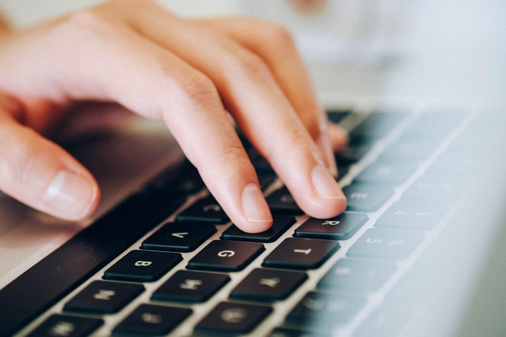 Close-up of hands typing on a laptop keyboard