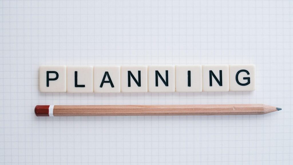 Letter tiles spelling PLANNING next to a pencil on graph paper