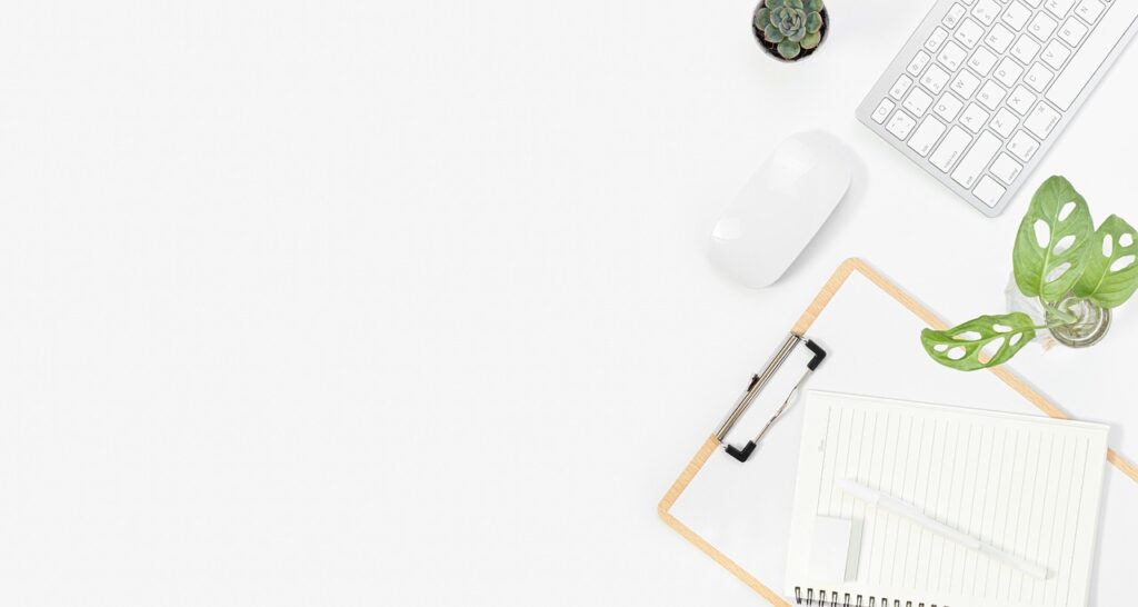 A minimalist desk with a keyboard, mouse and open notebook