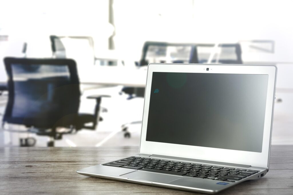 An open laptop on a wooden desk in a quiet office space