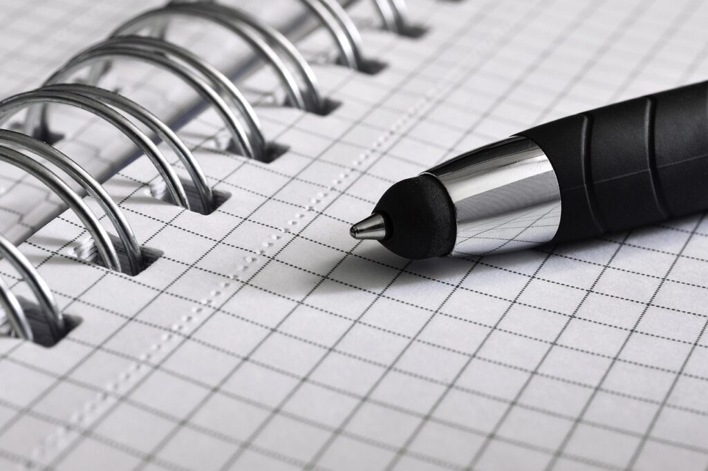 A pen resting on an open grid-paper notebook